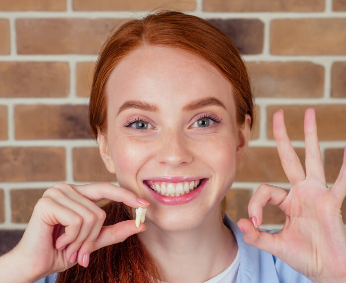 Smiling woman holding a tooth